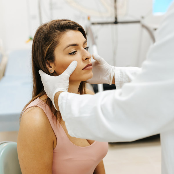 woman getting her face examined by doctor