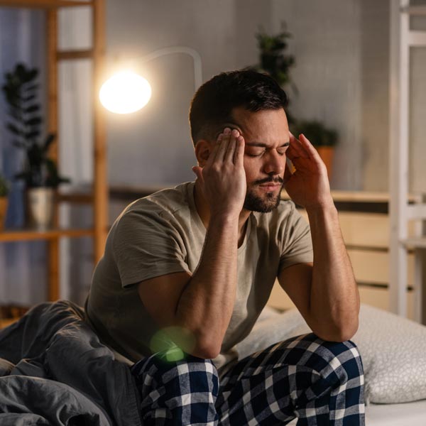 man holding head in pain unable to sleep
