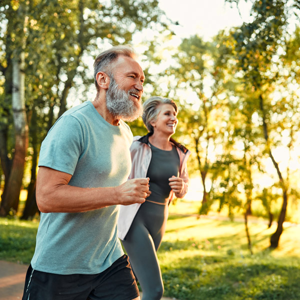 senior couple jogging through woods