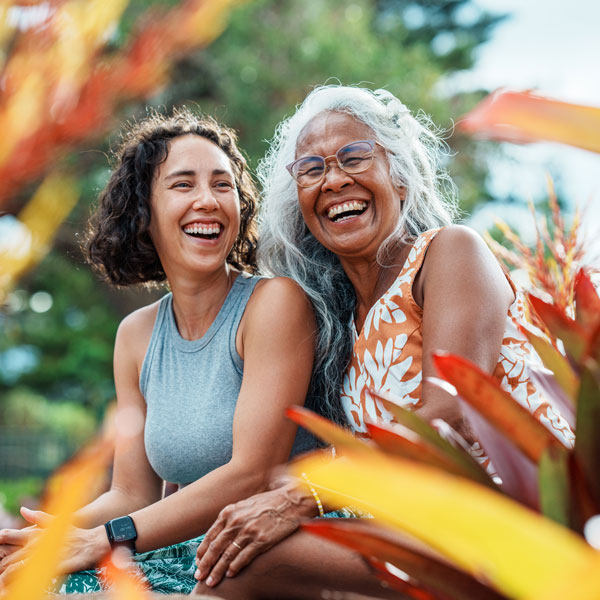mom and daughter laughing outdoors near colorful plants